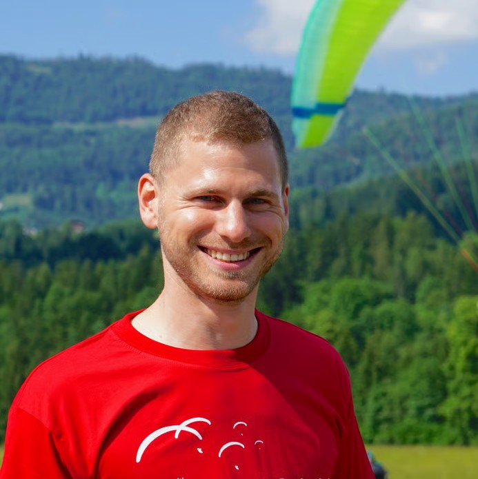 Philipp Hänggi lächelt in rotem Shirt vor einer Berglandschaft.