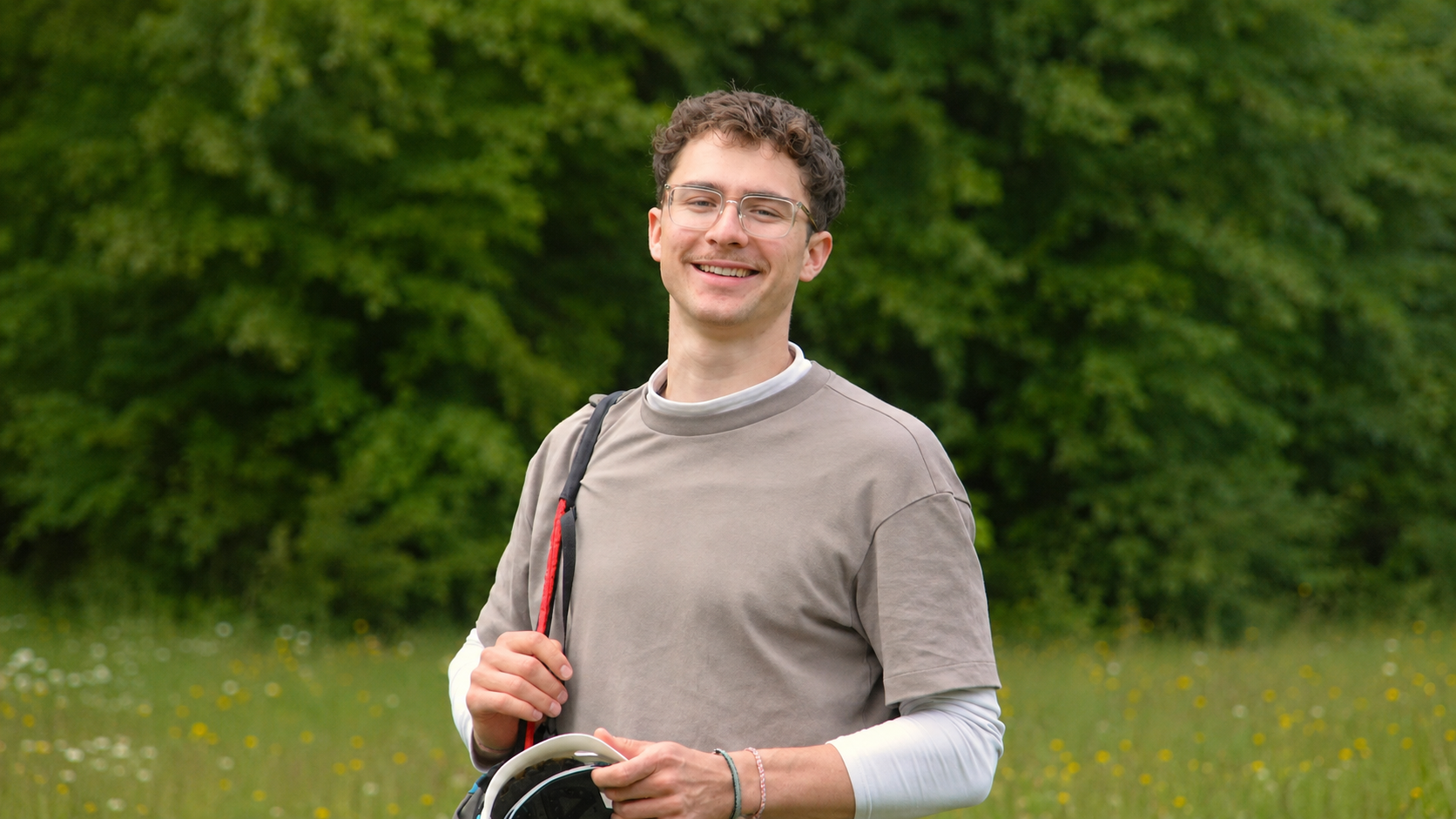 Tandempilot Max Mayer lächelt mit Gleitschirm-Ausrüstung im Grünen