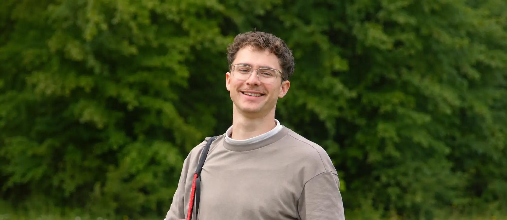 Tandempilot Max Mayer lächelt mit Gleitschirm-Ausrüstung im Grünen
